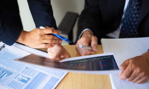 Investor and broker discussing trading strategy, holding papers with financial charts and pens. Cropped shot. Broker job or investment concept