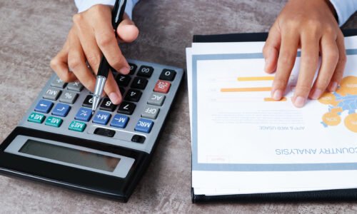 Closeup of analyst using calculator. Person working with diagram at desk. Marketing concept. Cropped view.