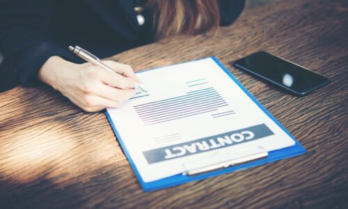 Happy business woman signing on document in a desk working at home.